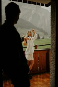 A couple stand on a porch in front of mountain in the Dolomites, Italy