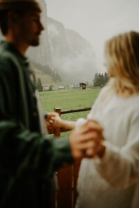A couple holds hands and looks out at the mountains in the Italian Dolomites