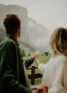 A couple holds hands and looks out at the mountains in the Italian Dolomites