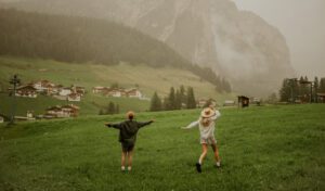 A couple spins around in a field in front of a mountain in the Dolomites, Italy  