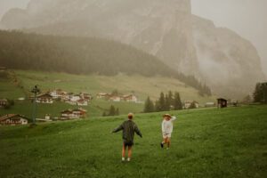 A couple spins around in a field in front of a mountain in the Dolomites, Italy  