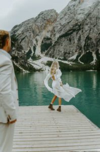 A bride and groom stand on the dock at Lago Di Braies in the Italian Dolomites