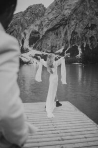 A black and white photo of a bride and groom on the dock at Lago Di Braies in the Italian Dolomites