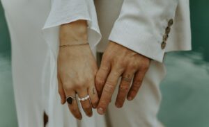 A couple holds hands showing their tattoo wedding rings