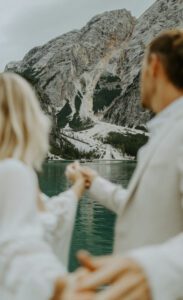 A photo of a bride and groom holding hands at their elopement at Lago Di Braies in the Italian Dolomites