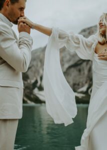 A groom kisses his brides hand at Lago Di Braies during their elopement