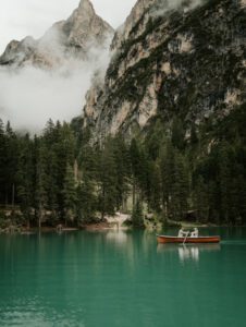 A bride and groom sit in a canoe at a foggy Lago Di Braies during their elopement