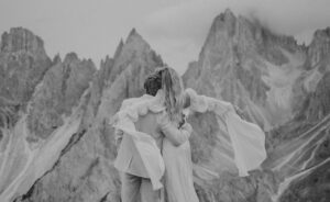 A black and white photo of an elopement couple standing in front of Cadini Di Misurina in the Italian Dolomites