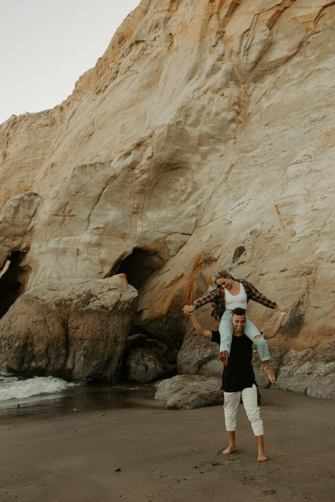 Couple beneath sandstone cliffs at Cape Kiwanda in Pacific City, Oregon during a coastal elopement