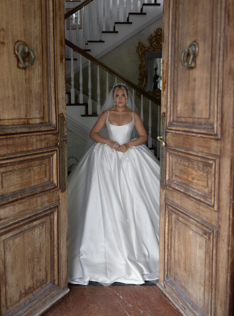 Bride standing in the historic wooden doors at La Caille wedding venue in Utah, highlighting the venue’s European-style design