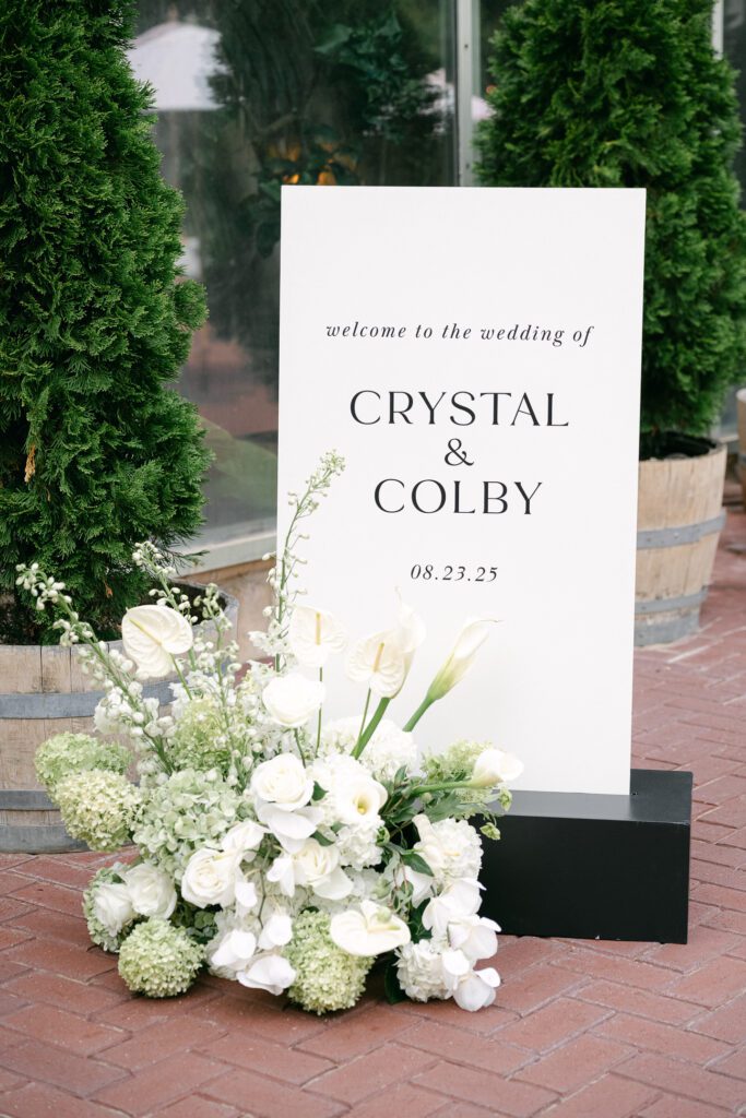 Wedding welcome sign and floral arrangement at La Caille wedding venue in Utah, styled with classic white blooms and greenery