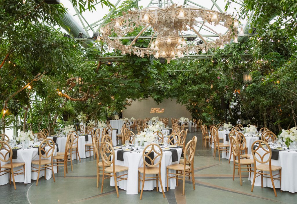 A greenhouse wedding reception with a chandelier and tables at La Caille Wedding Venue in Utah