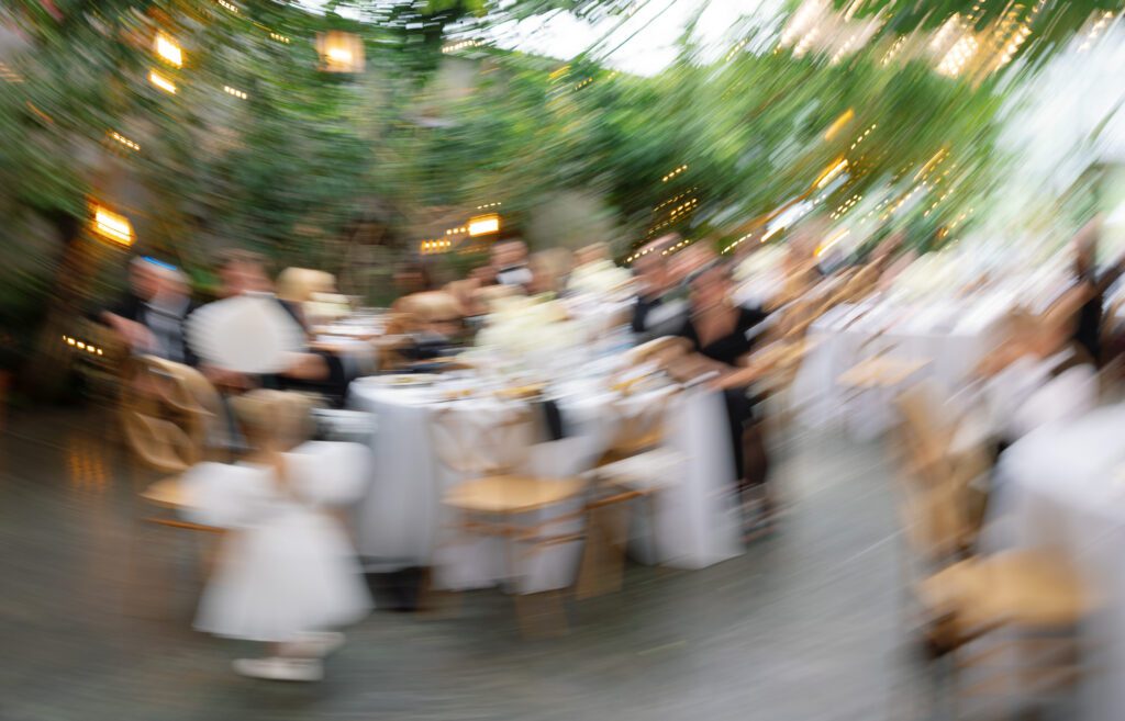 Wedding reception inside the La Caille greenhouse in Utah, capturing guests dining under string lights and lush greenery
