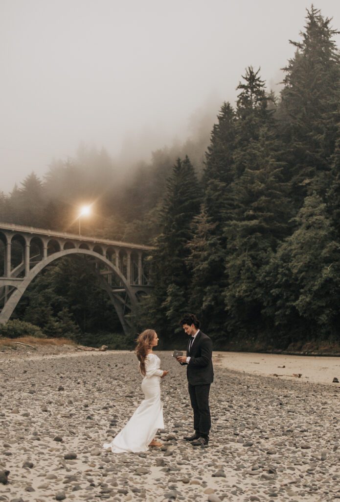 Couple exchanging vows beneath a coastal bridge near Heceta Head Lighthouse on the Oregon Coast