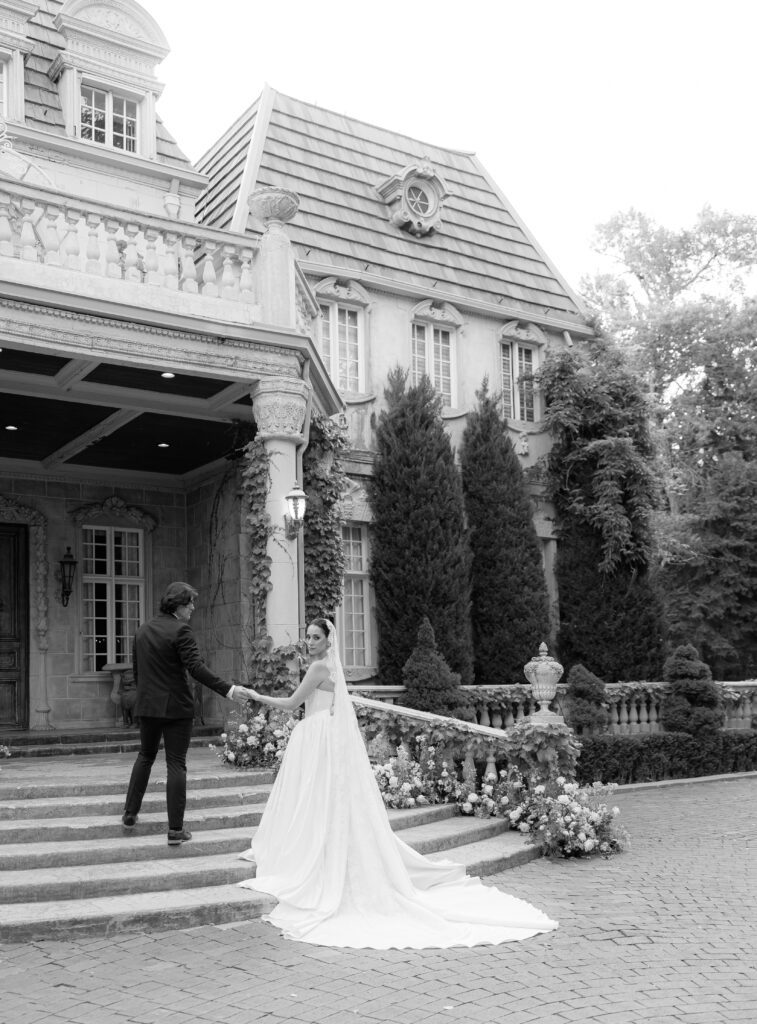 Bride and groom walking hand in hand outside La Caille wedding venue in Utah, framed by European-inspired stone architecture and manicured greenery