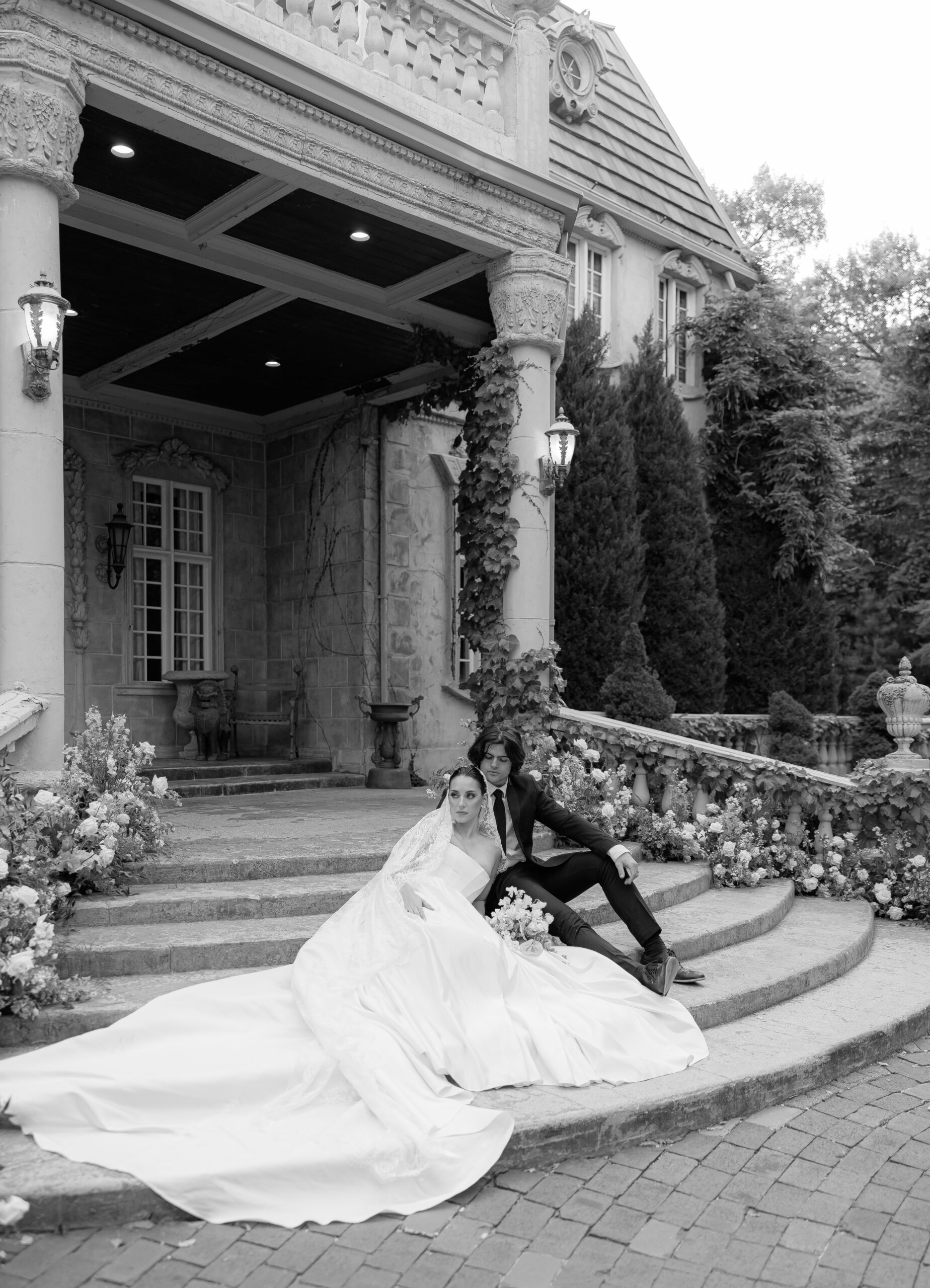 Black and white photo of a bride and groom on the steps of a French chateau