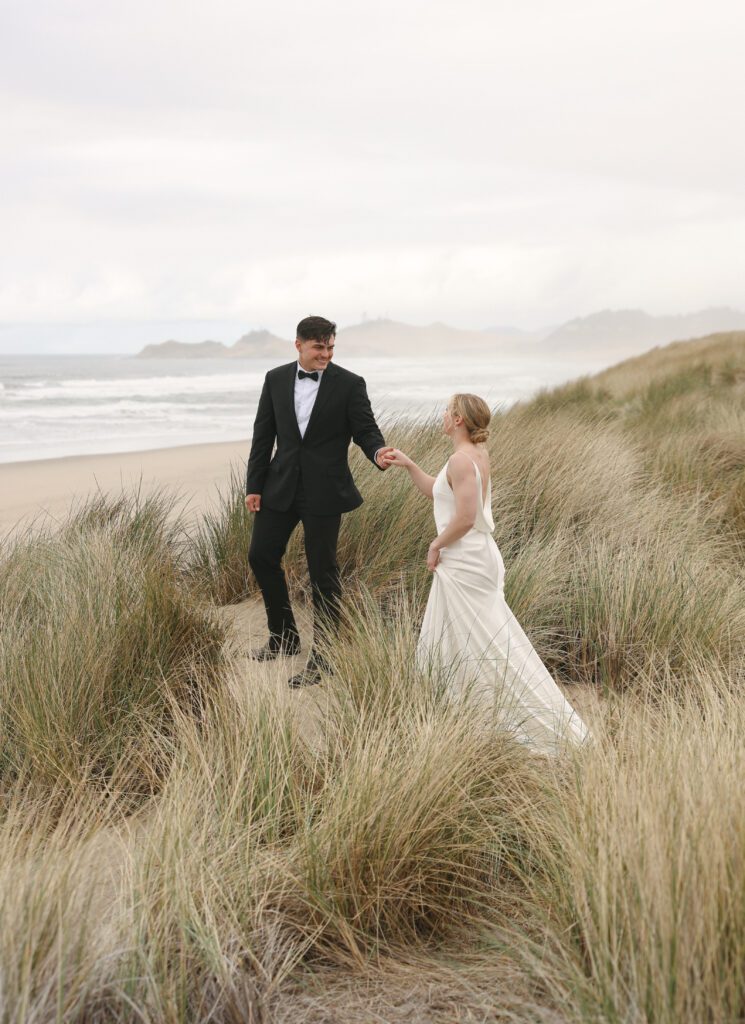 Bride and groom walking through beach grass at Bob Straub State Park during an Oregon Coast intimate elopement