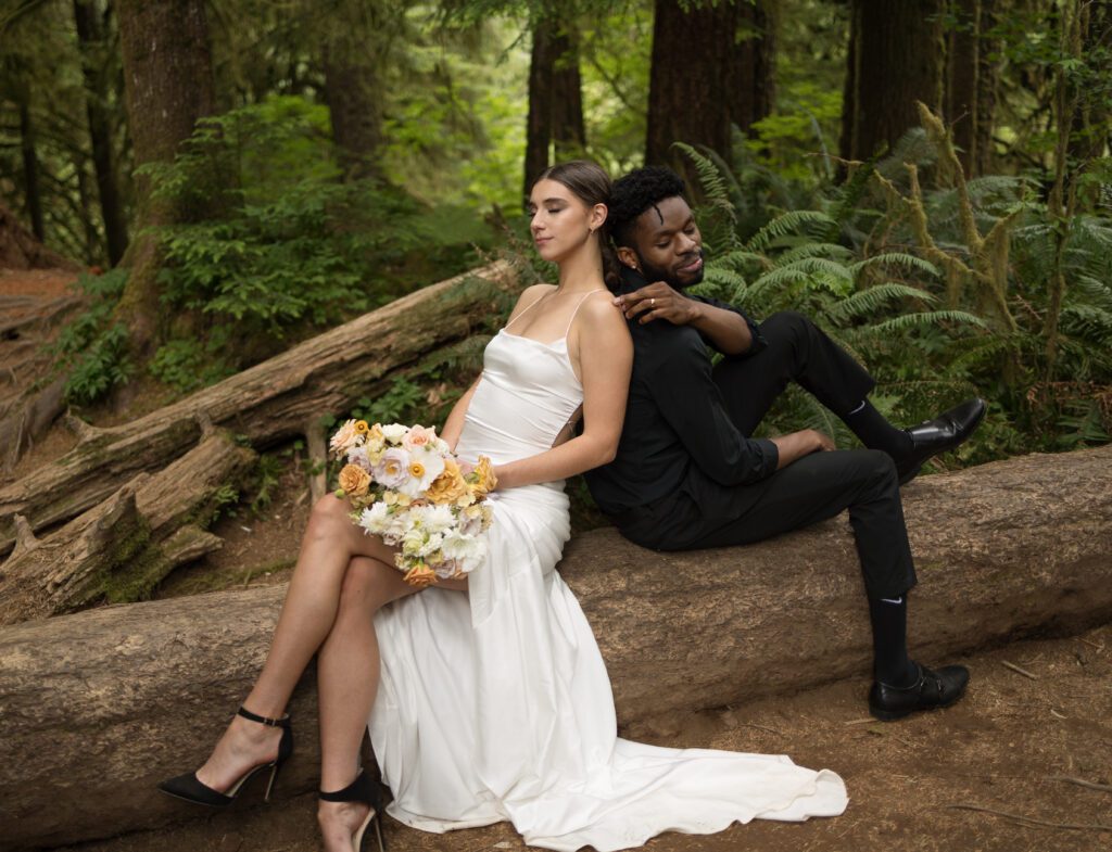 Couple seated on a fallen log in the forest near Drift Creek Falls Suspension Bridge in Oregon