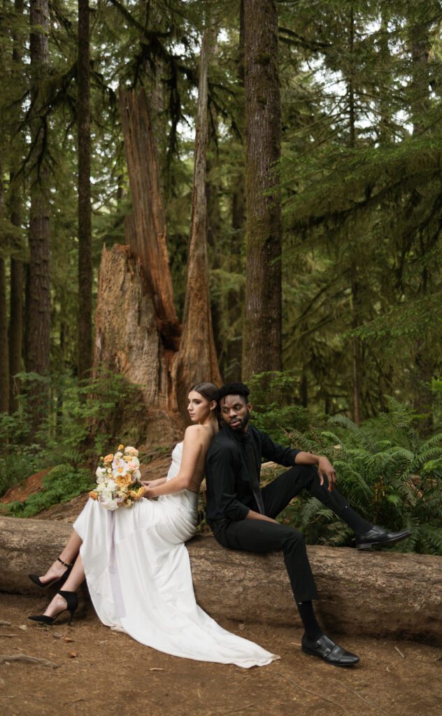 A bride and groom sitting on a log on the Oregon Coast
