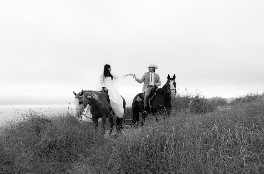 Bride and groom on horseback in coastal Oregon dunes during a romantic intimate wedding portrait