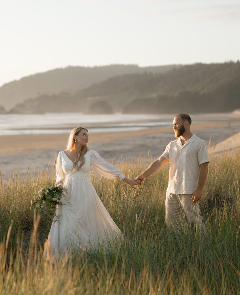 Couple walking through beach grass at Cannon Beach on the Oregon Coast during an intimate elopement