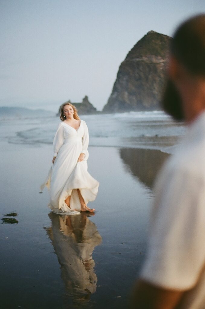A bride and groom at Cannon beach at sunset with Haystack Rock in the background