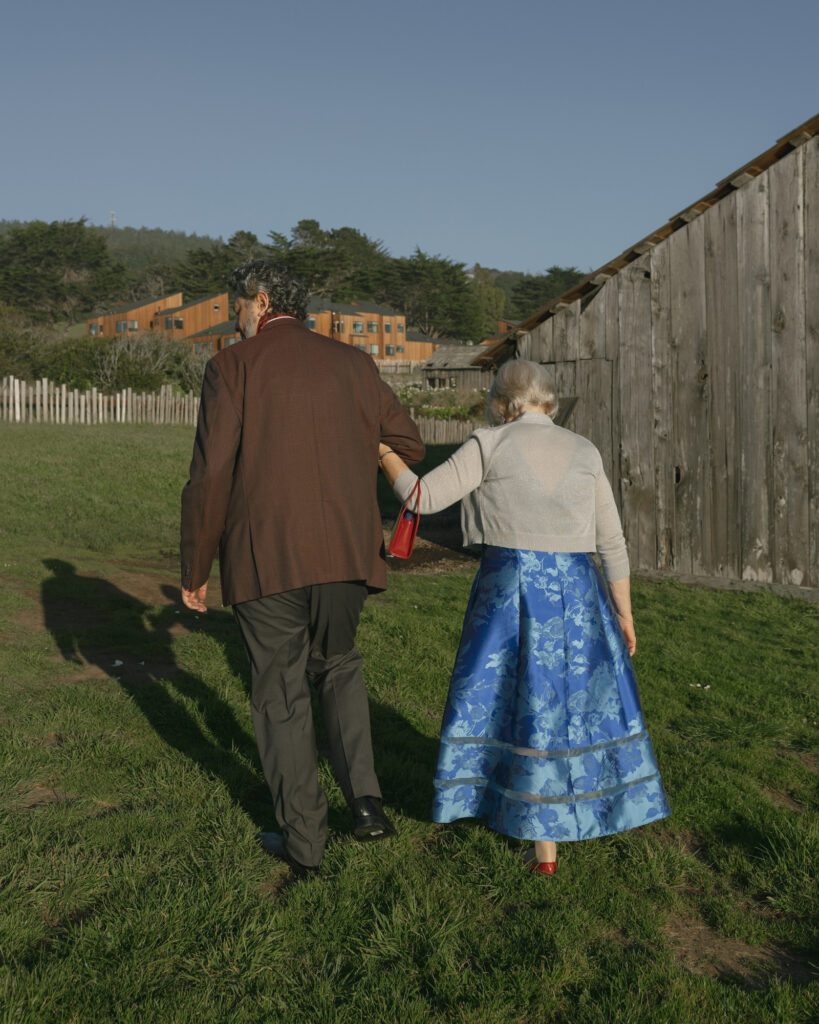 A grandmother and her adult son walk along a path after a wedding ceremony at the sea ranch lodge