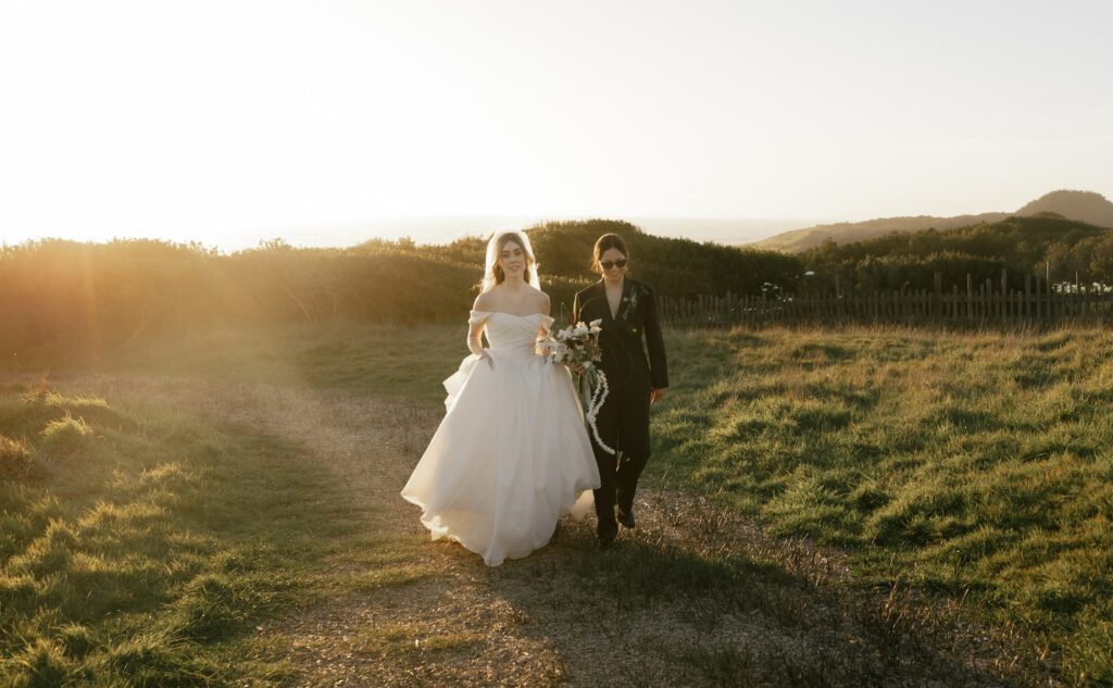 A bride and groom walk together on the ocean bluffs at the sea ranch lodge