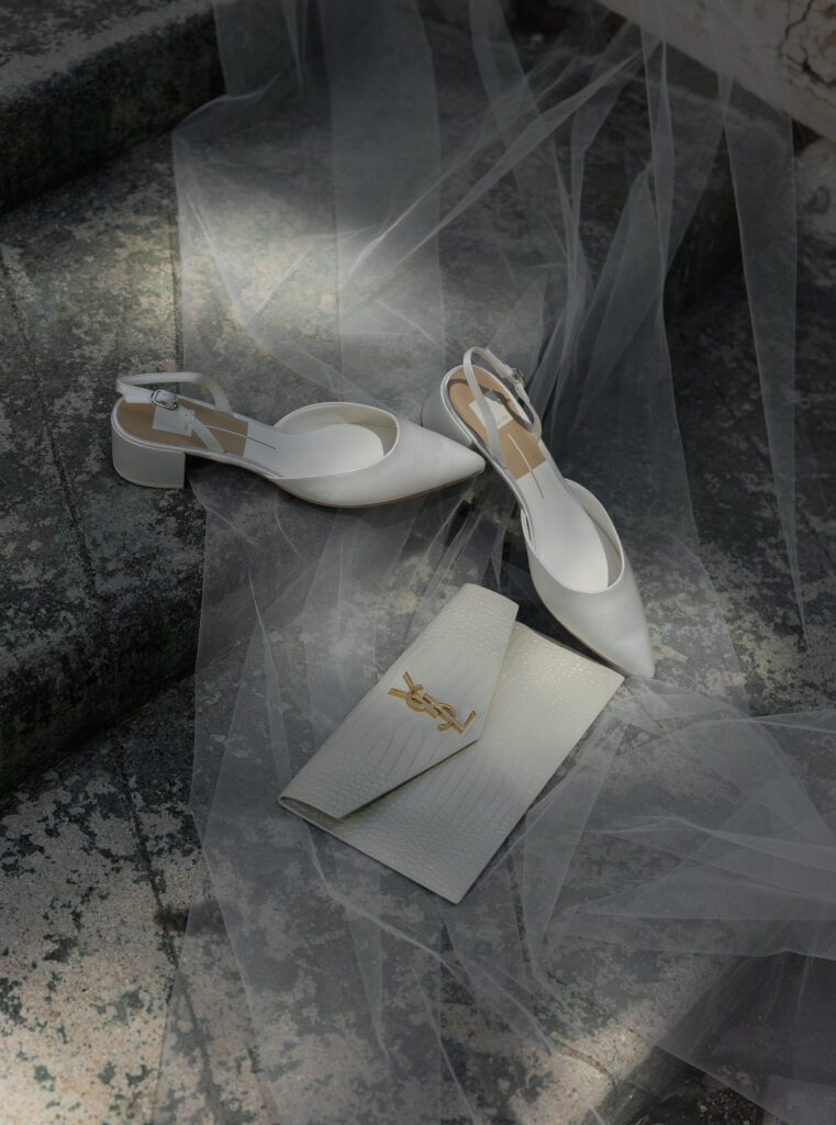 White bridal shoes and YSL clutch photographed with a wedding veil