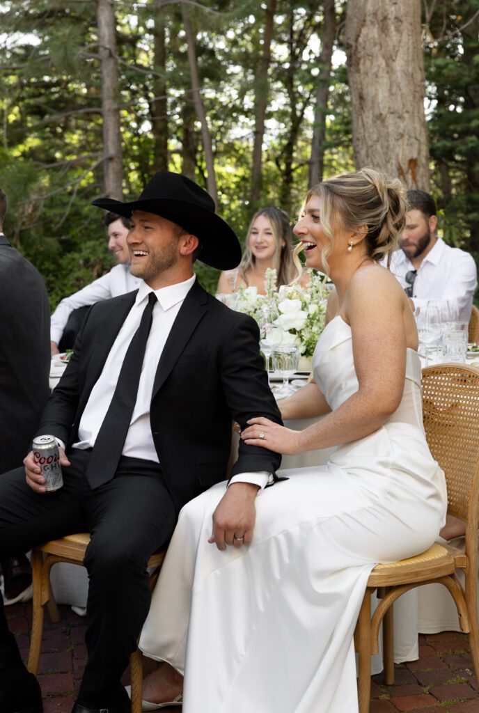 Bride and groom laughing during their outdoor wedding dinner at La Caille