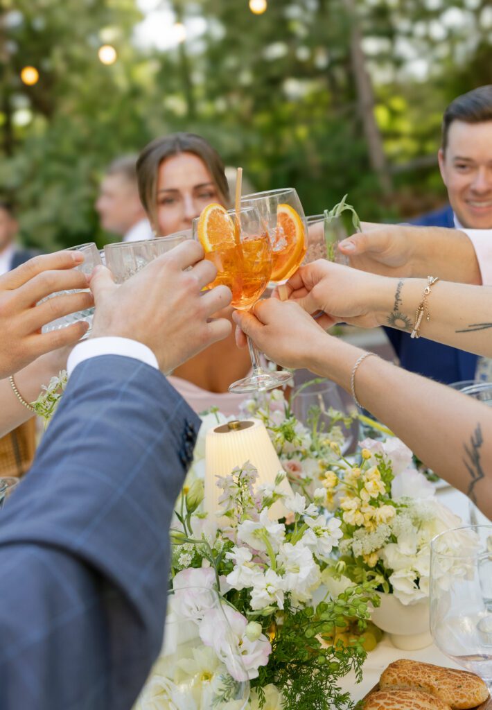 Wedding guests toast with Aperol spritzes during dinner at La Caille Utah